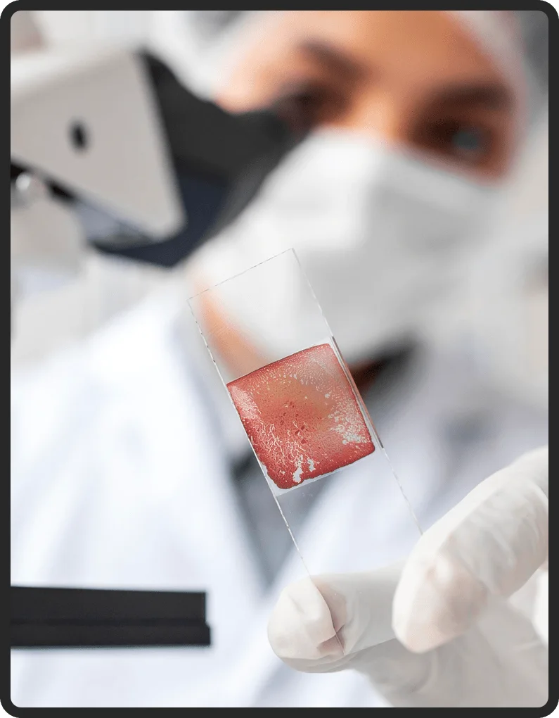 Researcher in a lab coat examining a sample slide in a research facility